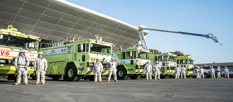 Airport Firemen in front of fire engines and other safety equipment.